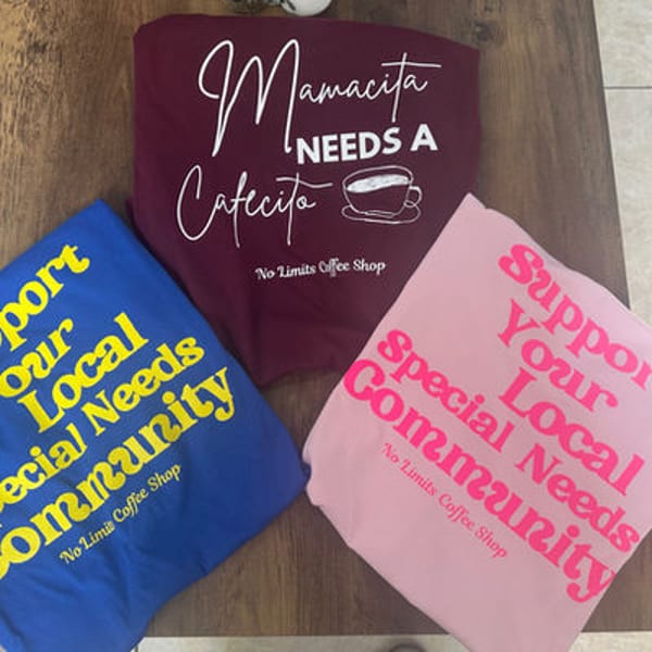 Three t-shirts, one burgundy, one blue, and one pink, with coffee-themed and community support slogans.