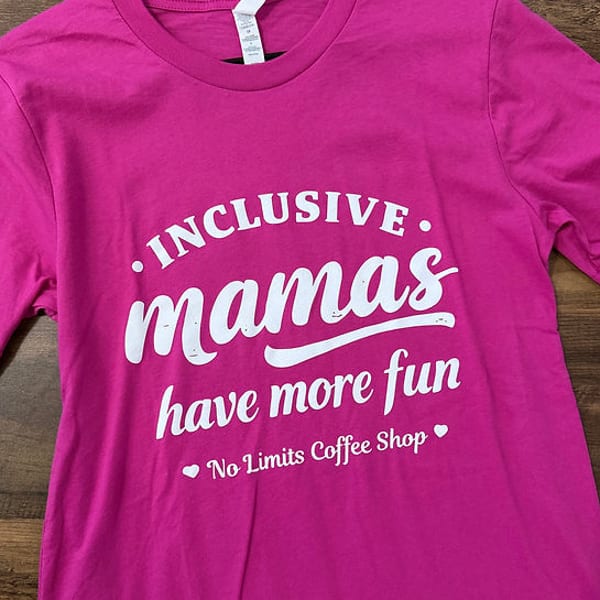 Bright pink t-shirt with "Inclusive mamas have more fun" and "No Limits Coffee Shop" in white text.