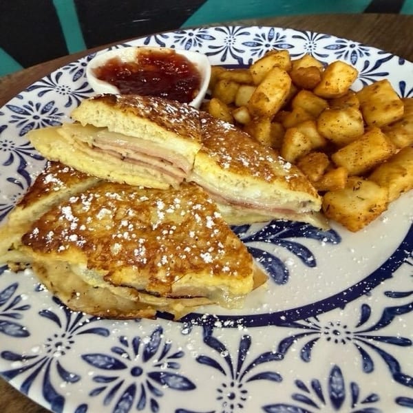 Savory French toast with ham and cheese, dusted with powdered sugar, served with home fries and jam.